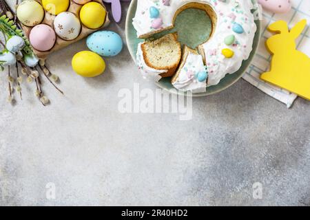 Glazed easter lemon cake decorated with confectionery and mini chocolate eggs candy on gray stone background. Happy Easter holid Stock Photo