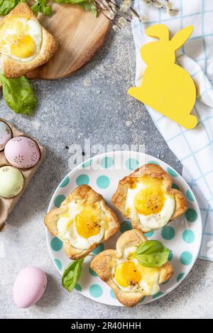 Easter breakfast idea. Scrambled eggs in puff pastry with cheese and bacon on a stone background. View from above. Copy space. Stock Photo