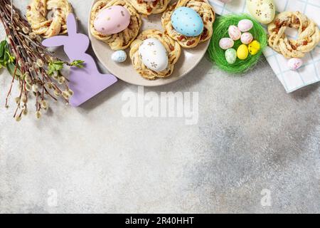 Easter composition. Sweet Italian Easter Bread Rings from puff pastry and dyed eggs on a stone background. View from above. Copy Stock Photo