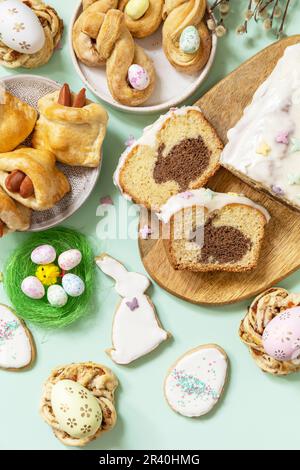 Festive dinner, Easter brunch. Happy Easter holiday food baking puff pastry and cupcake with Easter Bunny on pastel green backgr Stock Photo