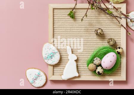 Springtime welcome layout. Letter board, colorful eggs and green branches on a pink background, minimalism style composition. Vi Stock Photo
