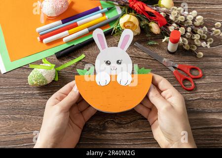 A child is holding an Easter card gift Easter bunny. Handmade. Project of children's creativity, handicrafts, crafts for kids. Stock Photo