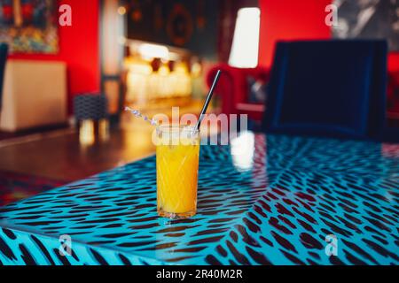 Crystal glass with orange cocktail and sprig of lavender on a bar blurred background Stock Photo