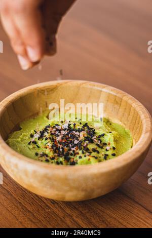 Bold de guacamole con semilla, esparciendo semillas con la mano Stock Photo