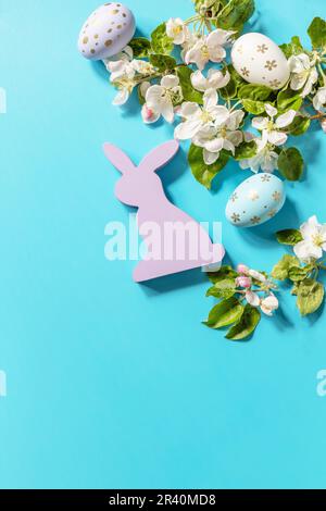 Easter composition with colorful eggs, wooden bunny and spring flowers on a blue background. Spring concept, flowers composition Stock Photo