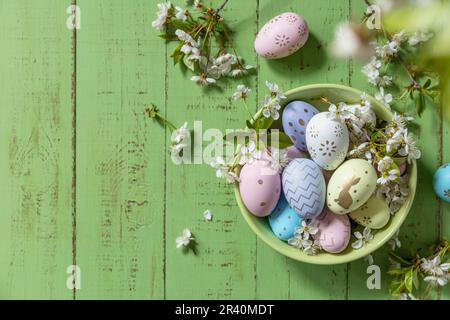 Easter composition. Branches of a blooming apple tree, handmade Easter colorful eggs on a pastel rustic wooden table. Happy East Stock Photo