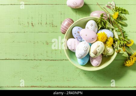 Happy Easter Holidays. Handmade Easter colorful eggs and spring flowers dandelions on a rustic wooden table. Easter composition. Stock Photo