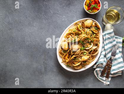 Seafood Pasta. ITALIAN SPAGHETTI ALLE VONGOLE. Clams spaghetti on white plate with white wine, gray background. Top view Stock Photo