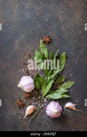 Culinary food background. Bay leaves with garlic, bay leaves and pepper on a stone dark table. Top view flat lay background. Cop Stock Photo