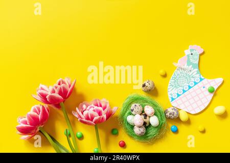 Colorful Easter background. Holiday greeting card with painted eggs, pink tulip. Top view flat lay. Copy space. Stock Photo