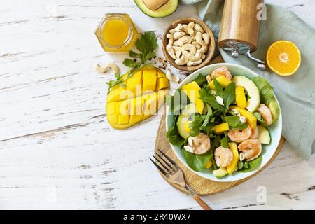 Vegetarian vegan healthy food. Salad with arugula, mango, avocado, shrimp, pecans and dressing of olive oil, honey and wine vine Stock Photo
