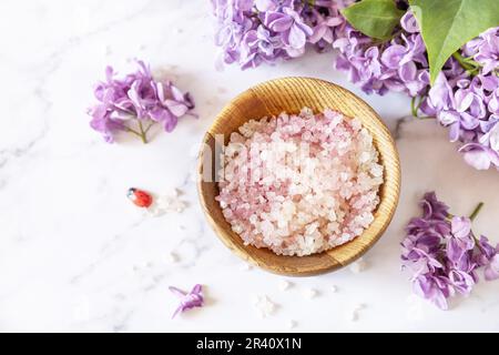Spa setting. Organic spa sea salt and lilac flowers on a marble.  Copy space. Stock Photo