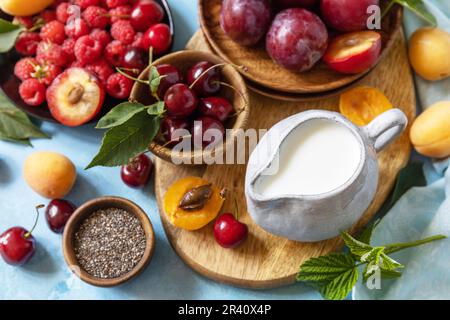 Ingredients for a healthy smoothie. Milk and berries (raspberry, cherry, plum, apricot) on a stone tabletop. Healthy eating, raw Stock Photo