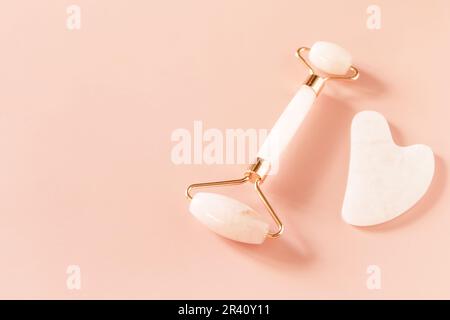 Rose quartz facial massage roller on a pink background. Massage tools with jade stone, anti-aging, anti-wrinkle beauty skincare Stock Photo