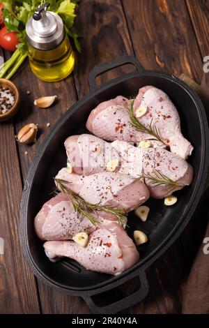Raw chicken meat. Uncooked chicken legs on wooden cooking table background with spices. Stock Photo