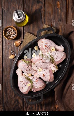 Raw chicken meat. Uncooked chicken legs on wooden cooking table background with spices. View from above. Stock Photo