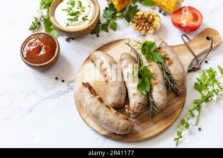 Grill food menu. Summer Party Food. Grilled Sausages with fresh herbs and spices on marble tabletop. Stock Photo