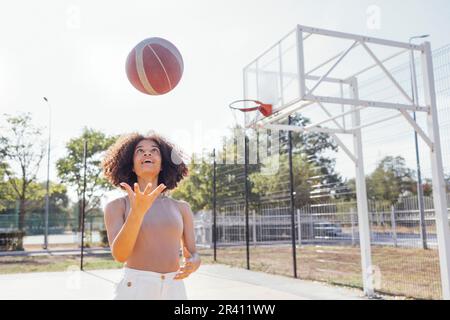 Stylish cool teen girl gathering at basketball court, playing basketball outdoors Stock Photo