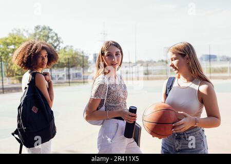 Tylish cool teen girls gathering at basketball court, friends ready for playing basketball outdoors Stock Photo