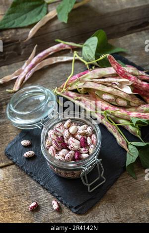 Beans of bean, brown bean (of dried beans) in a glass jar on a rustic table. Food background. Stock Photo