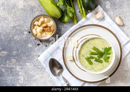 Healthy food. Vegan soup puree of green vegetables. Bowl of green bean and zucchini cream soup on a stone table. View from above Stock Photo