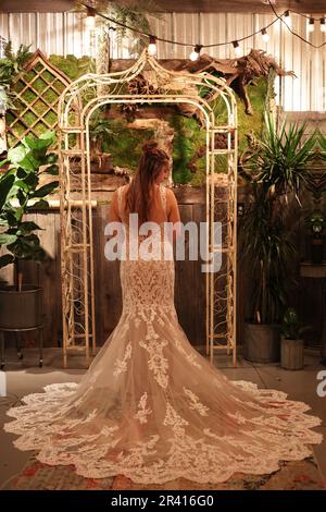 Bride in A White Dress Looks Over Her Shoulder at the Alter During Wedding Stock Photo