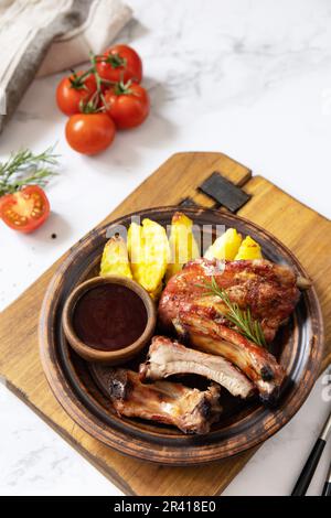 BBQ grilled veal calf brisket meat and french fries potatoes with sauce on a marble tabletop. Copy space. Stock Photo