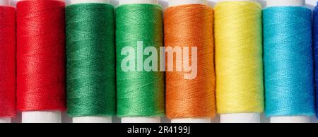 Multicolored spools of sewing threads on a white background, top view Stock Photo