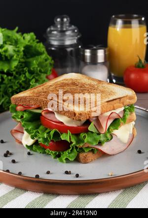 Sandwich with ham, cheese and vegetables on plate, on black background Stock Photo