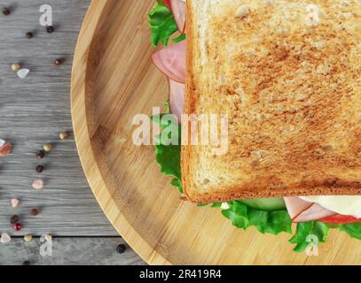 Sandwich with ham, cheese and lettuce on a wooden board. Stock Photo