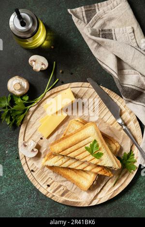 Delicious sandwich with grilled cheese, bacon and mushroom. Homemade breakfast on a dark stone tabletop. View from above. Stock Photo