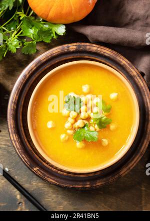 Comfort food, fall and winter healthy slow food concept. Vegetarian pumpkin and chickpea cream soup on a rustic wooden table. Vi Stock Photo