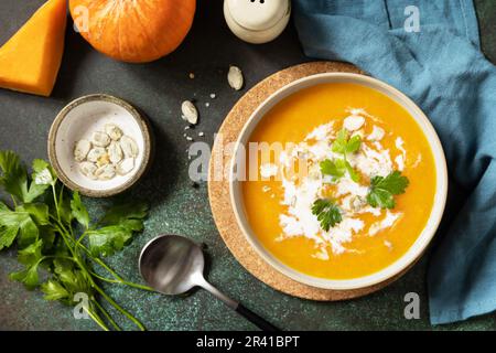 Vegetarian pumpkin and carrot cream soup with cream and pumpkin seeds on a stone tabletop. Comfort food, fall and winter healthy Stock Photo