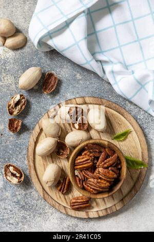 Nuts and seeds, healthy fats, various trace elements and vitamins. Bowl with pecan nuts on a stone table. View from above. Stock Photo