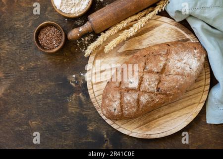 Homemade baking. Bread from whole wheat grains, wheat bran, seeds, bio-ingredients over rustic table background, healthy lifesty Stock Photo