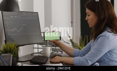 Office manager looking at horizontal greenscreen on digital device ...