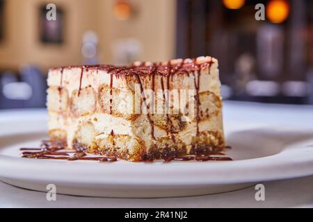 Dessert dish tiramisu Italian ladyfingers sweet sugar treat chocolate drizzle white plate background Stock Photo
