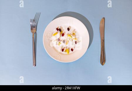 Tablets, pills and capsules on a white porcelain plate. The table is set with a plate Stock Photo