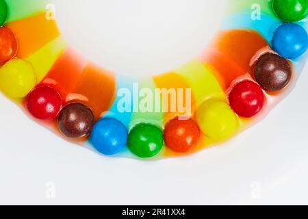 Smile of rainbow colors from skittles candy mixing with water on white background Stock Photo