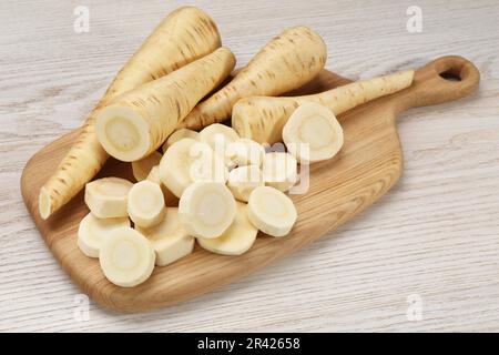 Whole and cut fresh ripe parsnips on white wooden table Stock Photo
