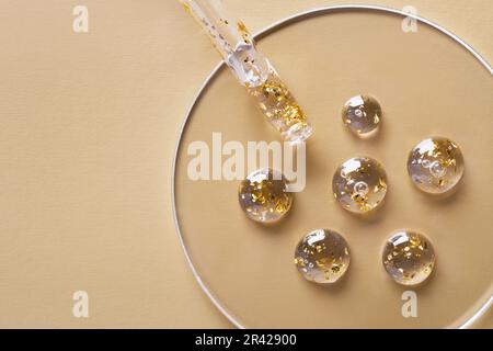 Samples of gel cosmetic products with gold in a Petri dish on beige background Stock Photo