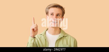 Young man with dental braces and raised index finger on beige background Stock Photo
