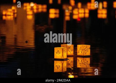 Japanese themed golden lanterns floating on dark waters Stock Photo