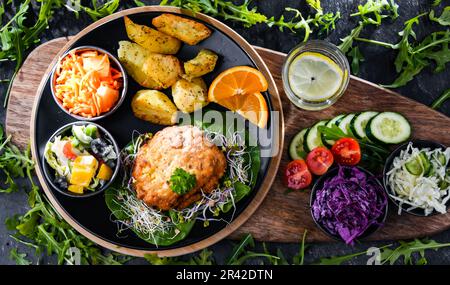 Pulled chicken cutlet coated with breadcrumbs with potatoes and vegetable salads Stock Photo