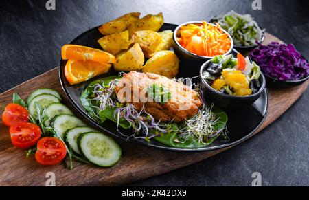 Pulled chicken cutlet coated with breadcrumbs with potatoes and vegetable salads Stock Photo