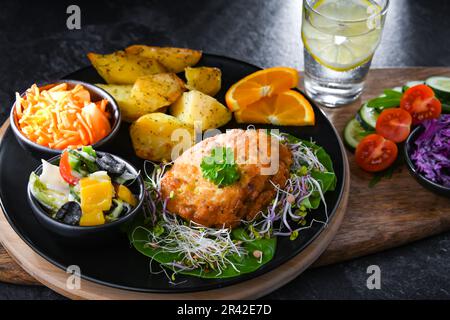 Pulled chicken cutlet coated with breadcrumbs with potatoes and vegetable salads Stock Photo