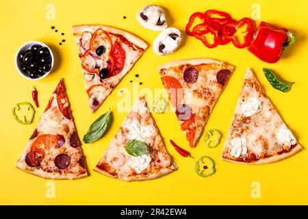 Selection of Assorted pieces pizza on yellow background and ingredients. Pepperoni, Vegetarian and Seafood Pizza Stock Photo