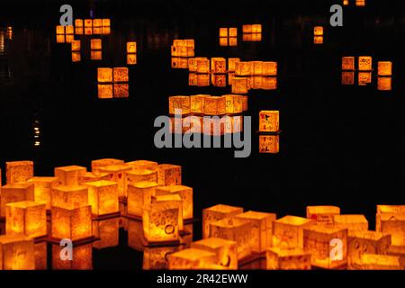 Golden glowing lanterns collecting in black waters at festival Stock Photo