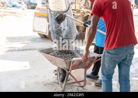 Workers load cement from trucks onto carts to pour the floor in areas that trucks can't reach. Stock Photo