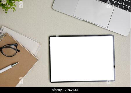 Minimal workspace with digital tablet white screen mockup, eyeglasses, laptop computer, school books, pen and decor plant on grey background. Stock Photo